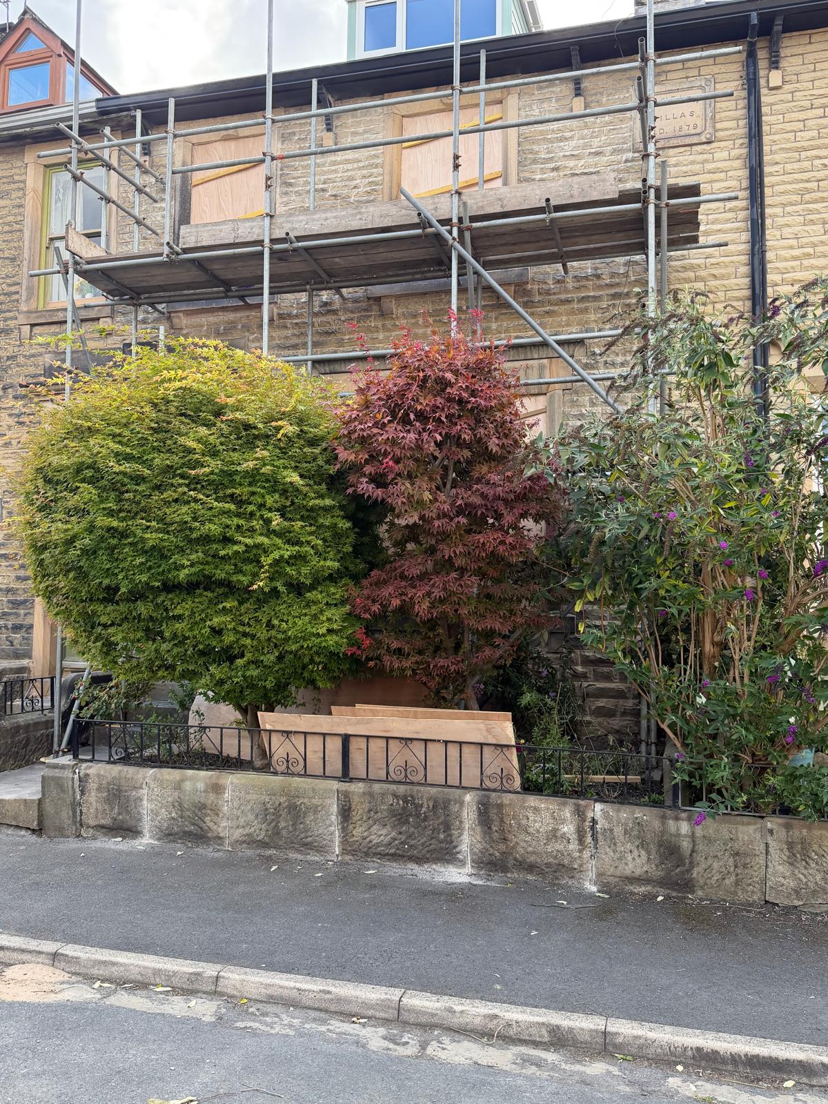 Stone frontage with scaffold and protected planting